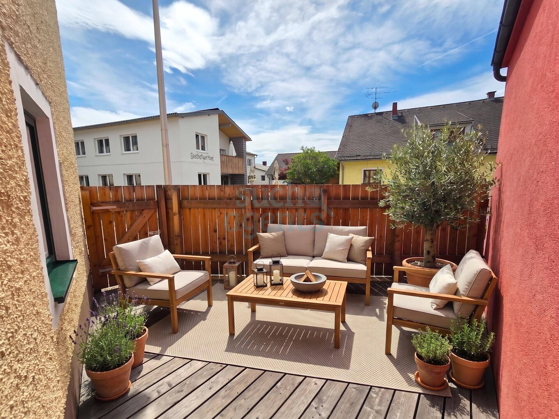 Gemütliche Terrasse mit Holzmöbeln, Pflanzen und Sichtschutz für entspannte Stunden im Freien.