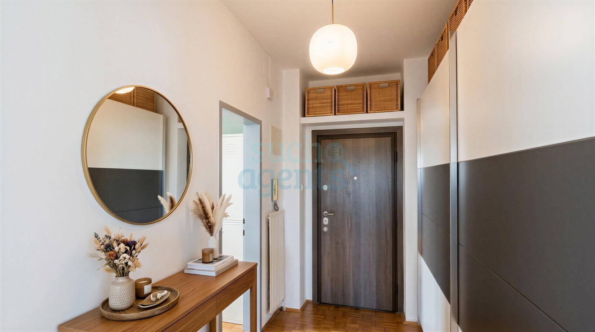 Heller Eingangsbereich mit Garderobe, rundem Spiegel und Holzboden.