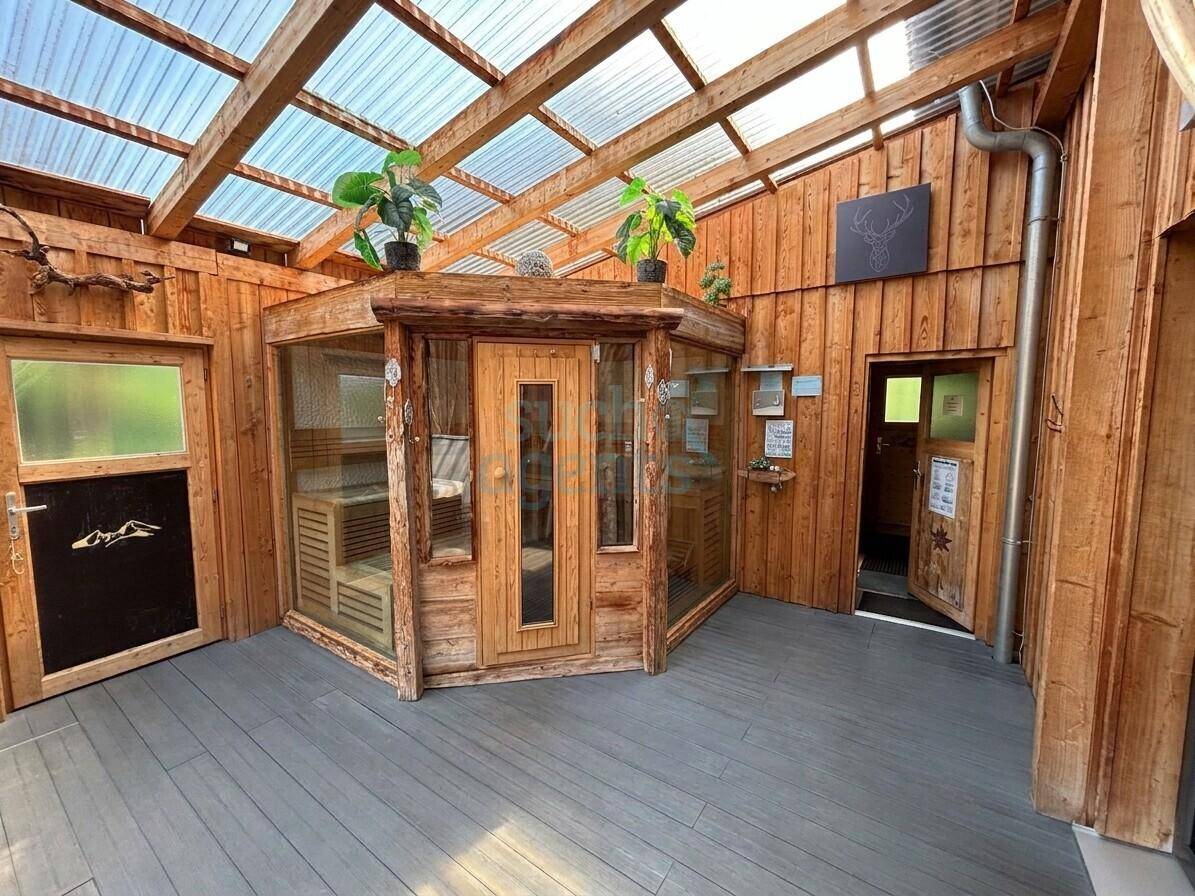 Heller Wellnessbereich mit Holzverkleidung, transparentem Dach und integrierter Sauna für Entspannung.