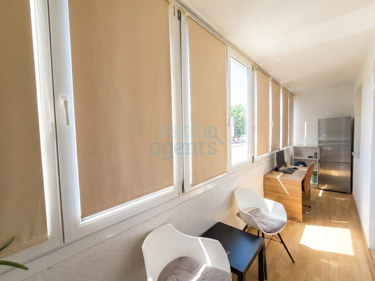 Heller Wintergarten oder verglaster Balkon, genutzt als Büro mit viel Tageslicht.