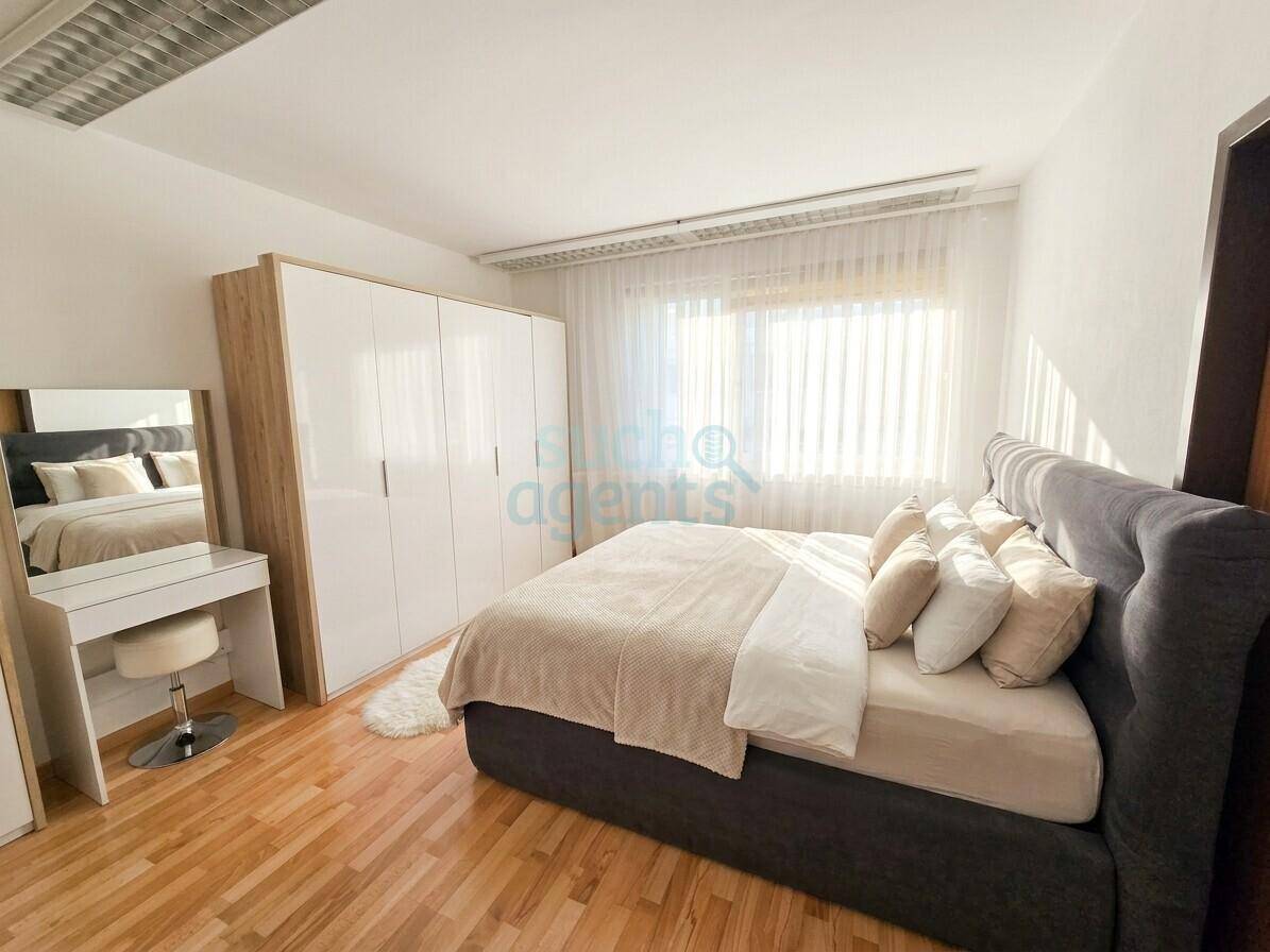 Helles Schlafzimmer mit Doppelbett, modernem Kleiderschrank und Schminktisch.