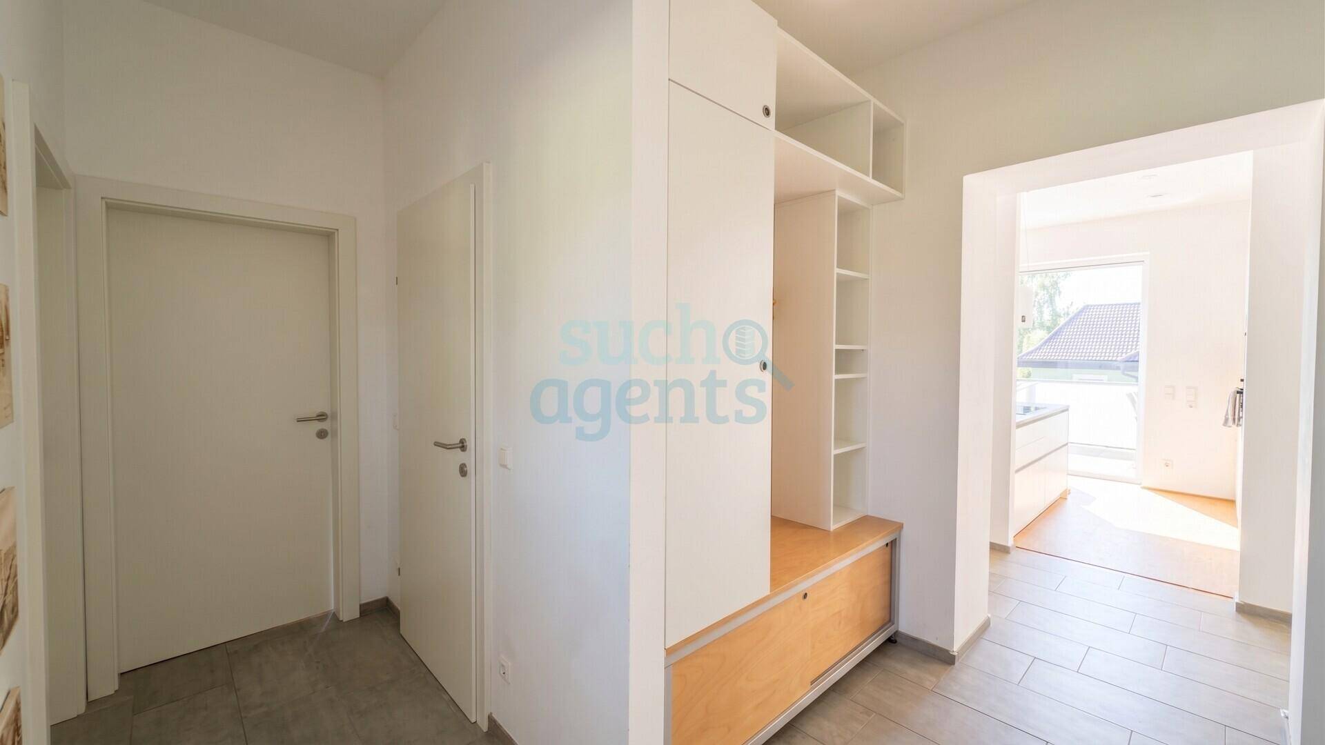 Heller Flur mit modernem Einbauschrank und Zugang zu einem lichtdurchfluteten Wohnbereich.