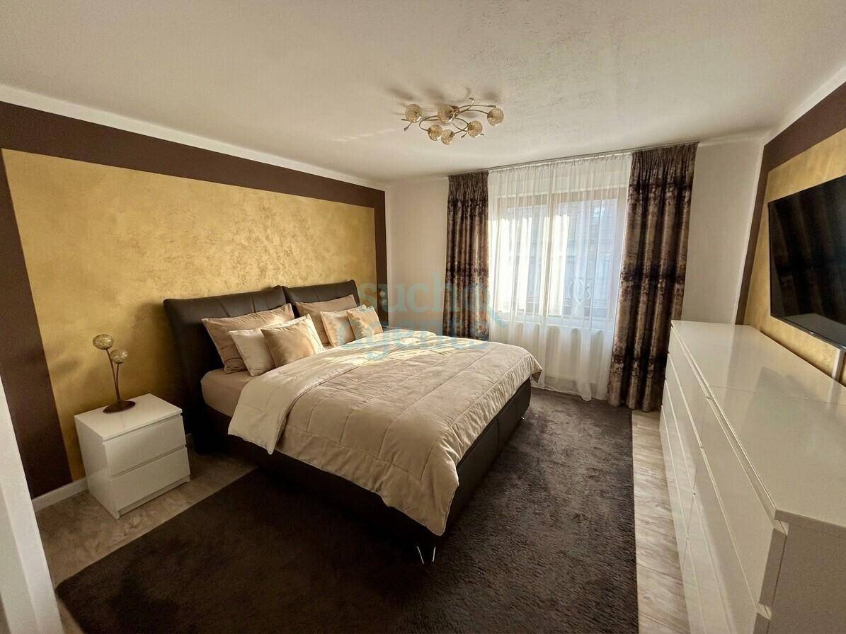 Gemütliches Schlafzimmer mit Doppelbett, Teppichboden und dekorativer Wandgestaltung in Goldtönen.