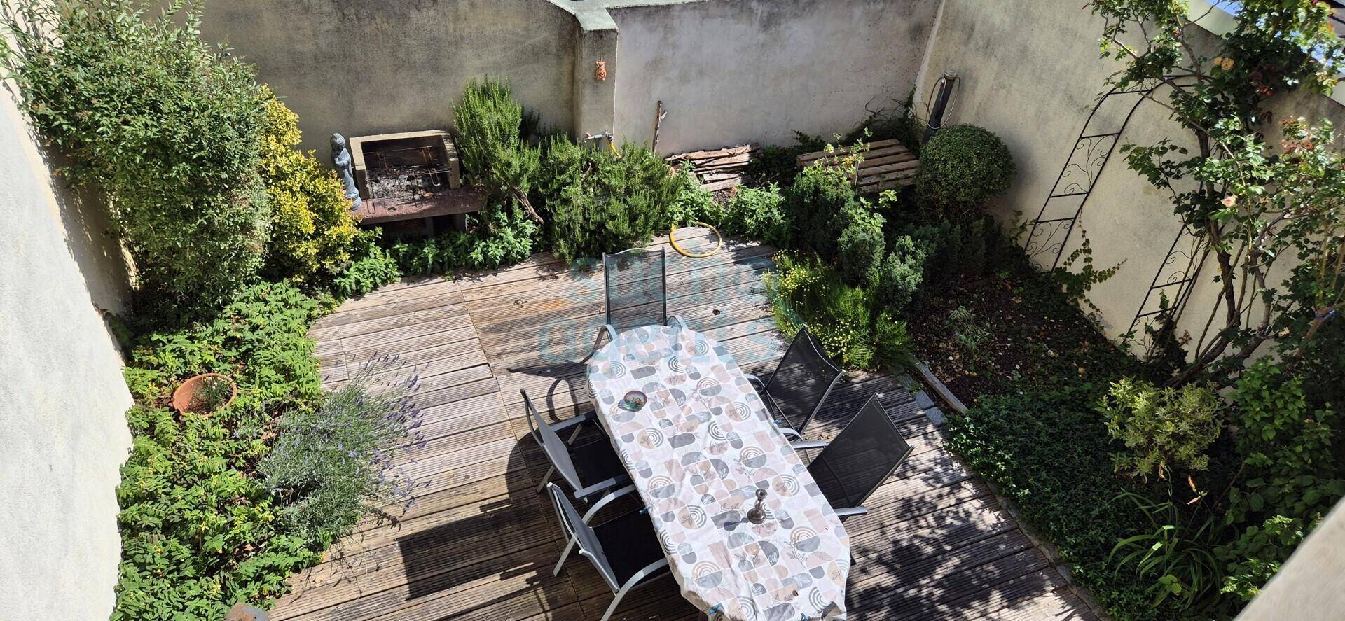 Gemütliche Holzterrasse mit Esstisch und umgebender Bepflanzung, ideal für Mahlzeiten im Freien.