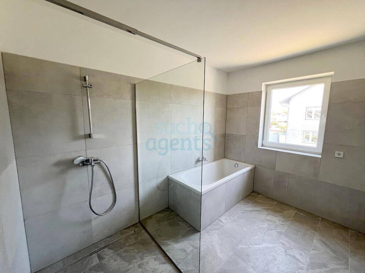 Modernes Badezimmer mit Badewanne, begehbarer Dusche und Fenster.