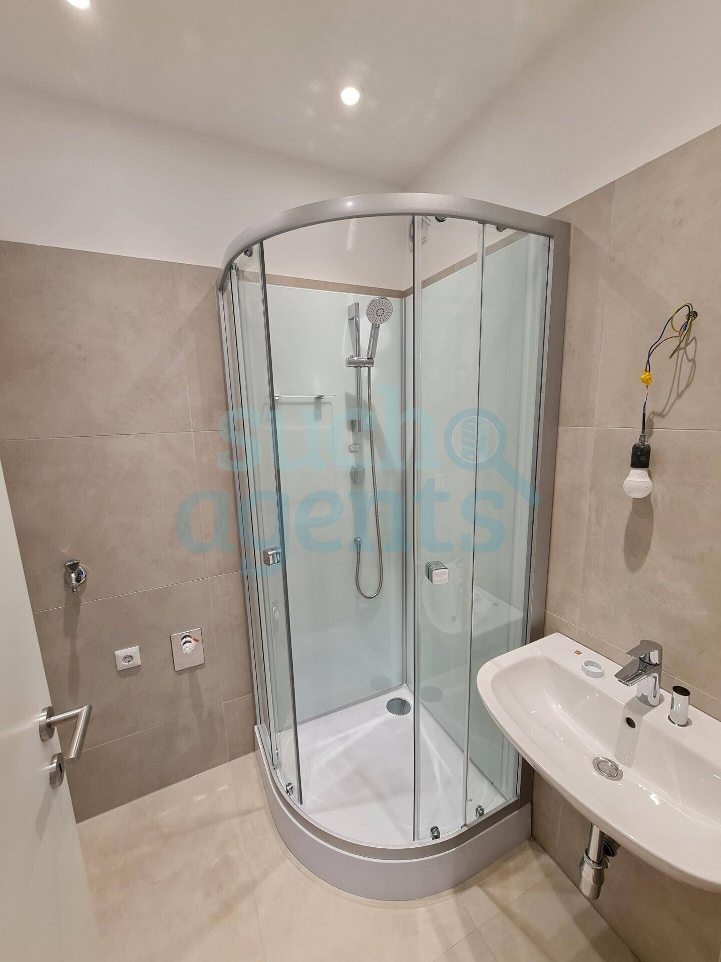 Modernes Badezimmer mit einer praktischen Eckduschkabine und einem eleganten Waschbecken, ausgestattet mit hellen Wand- und Bodenfliesen.