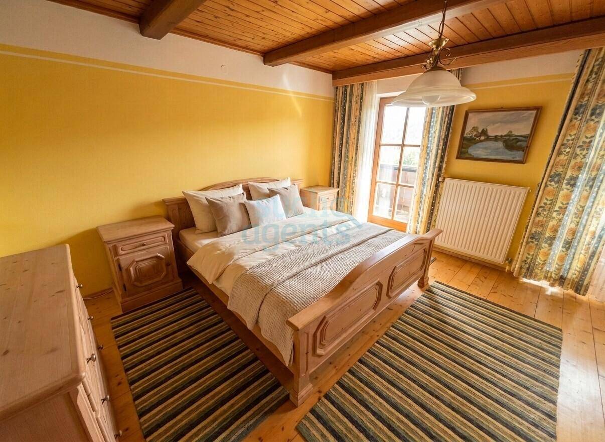 Gemütliches Schlafzimmer im Landhausstil mit Holzbalkendecke, Parkettboden und Balkonzugang.