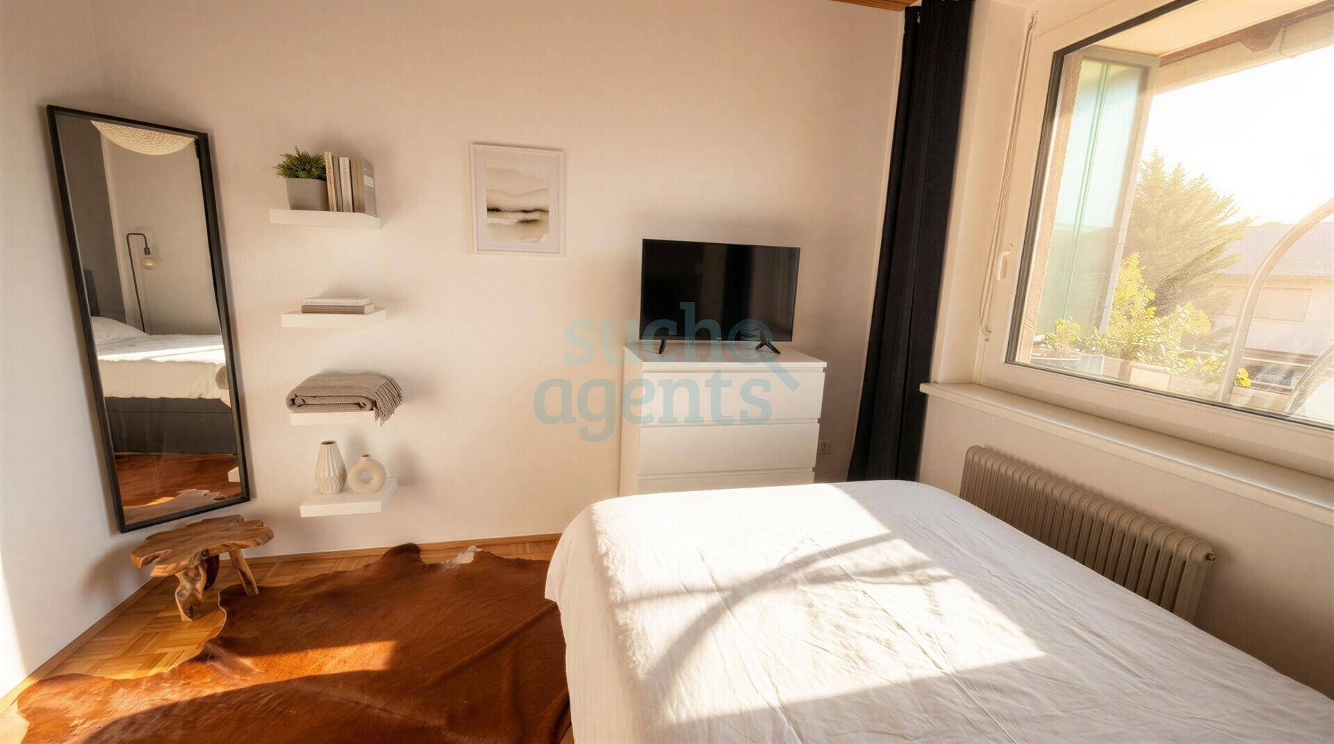 Helles Schlafzimmer mit großem Fenster, weißer Kommode und einem Ganzkörperspiegel.