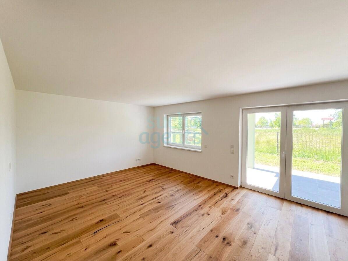 Heller, leerer Raum mit Holzboden und Zugang zu einer Terrasse oder dem Garten.