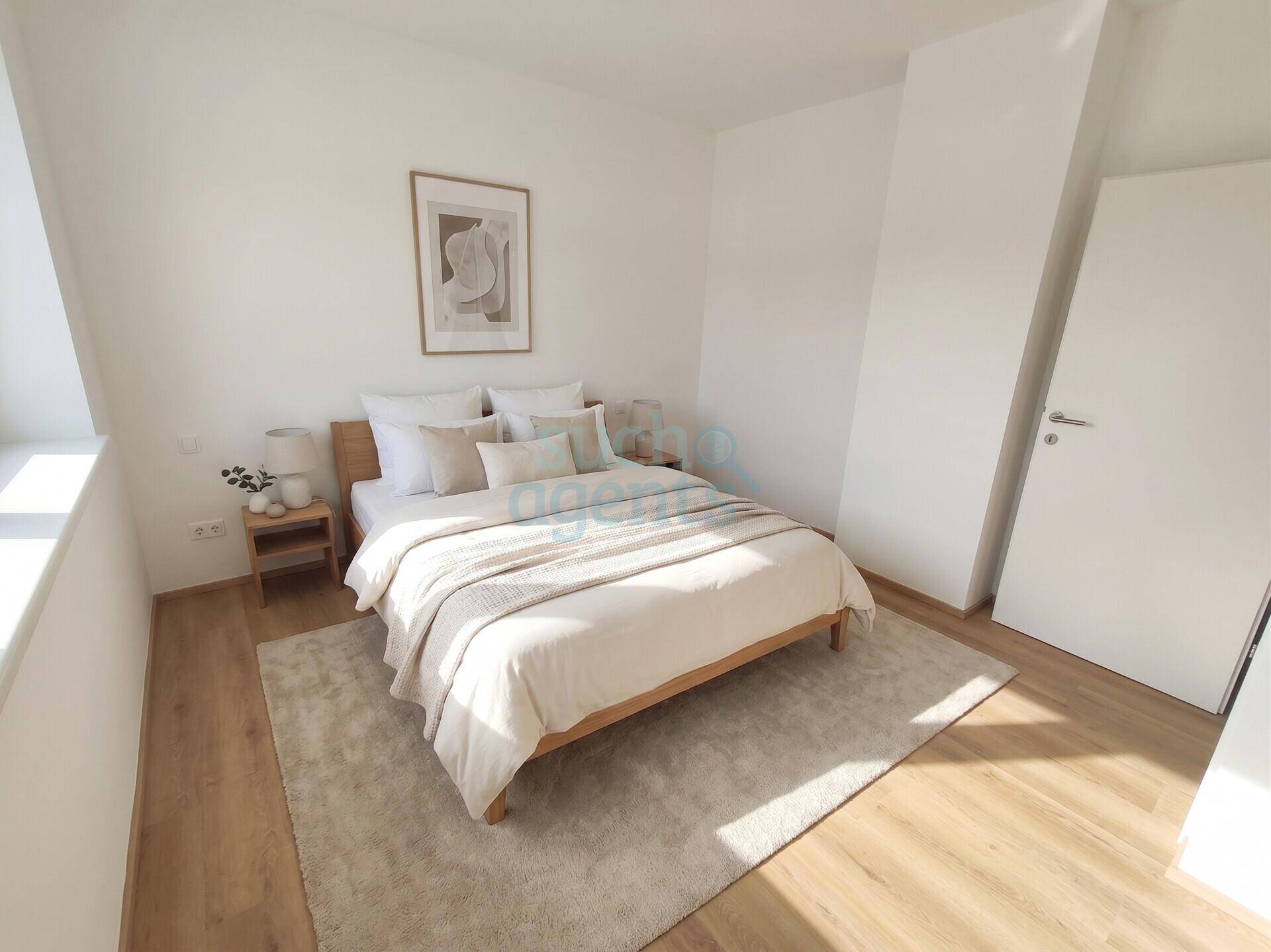 Modern eingerichtetes Schlafzimmer mit hellem Holzbett, Teppich und viel Tageslicht.