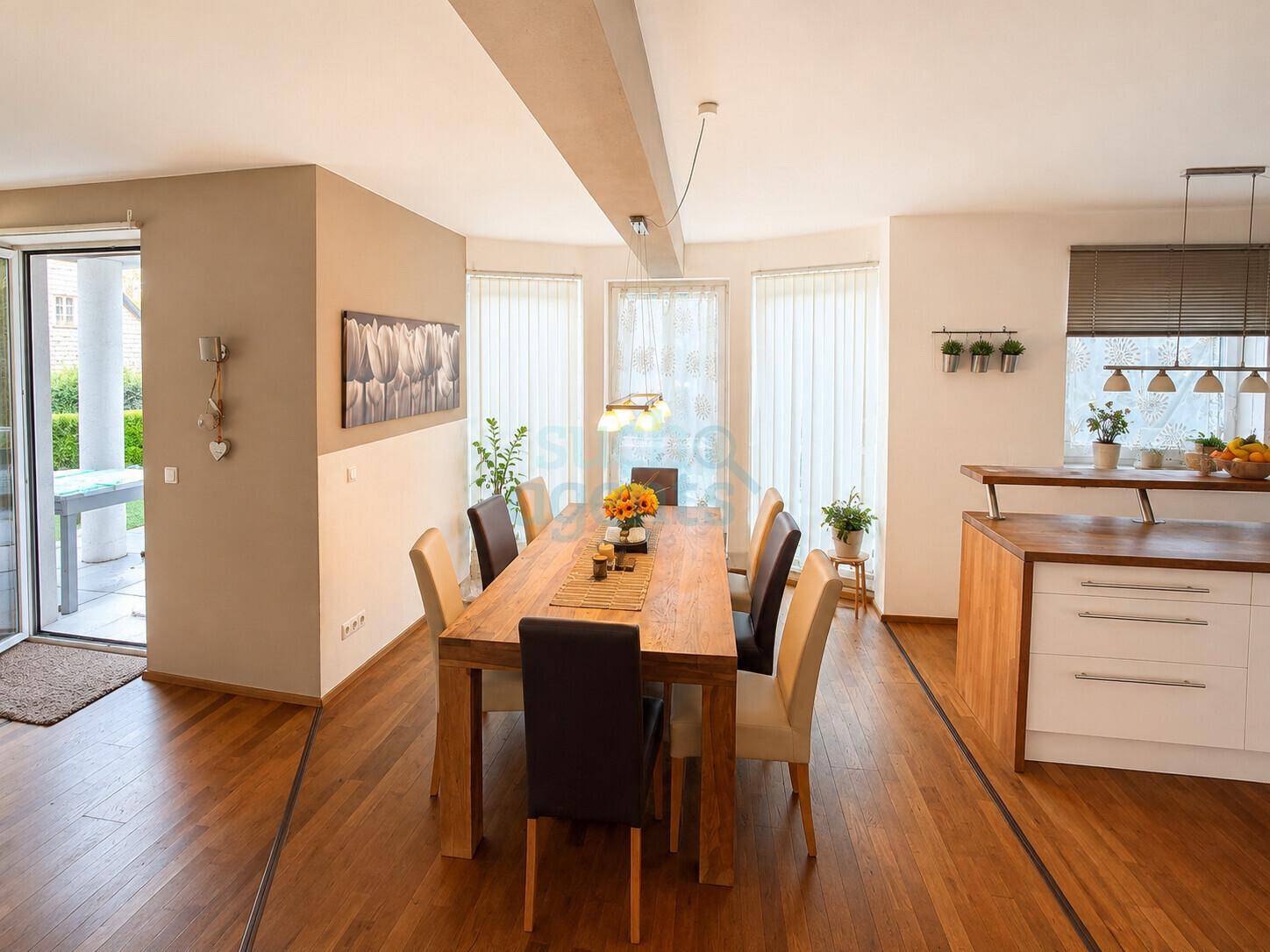 Heller Essbereich mit großem Holztisch, modernen Stühlen und Zugang zum Garten.