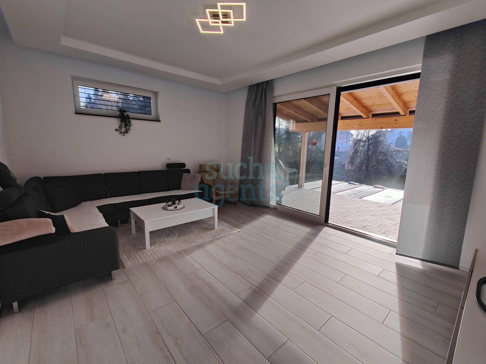 Helles Wohnzimmer mit modernem Sofa, Couchtisch und Zugang zur überdachten Terrasse.