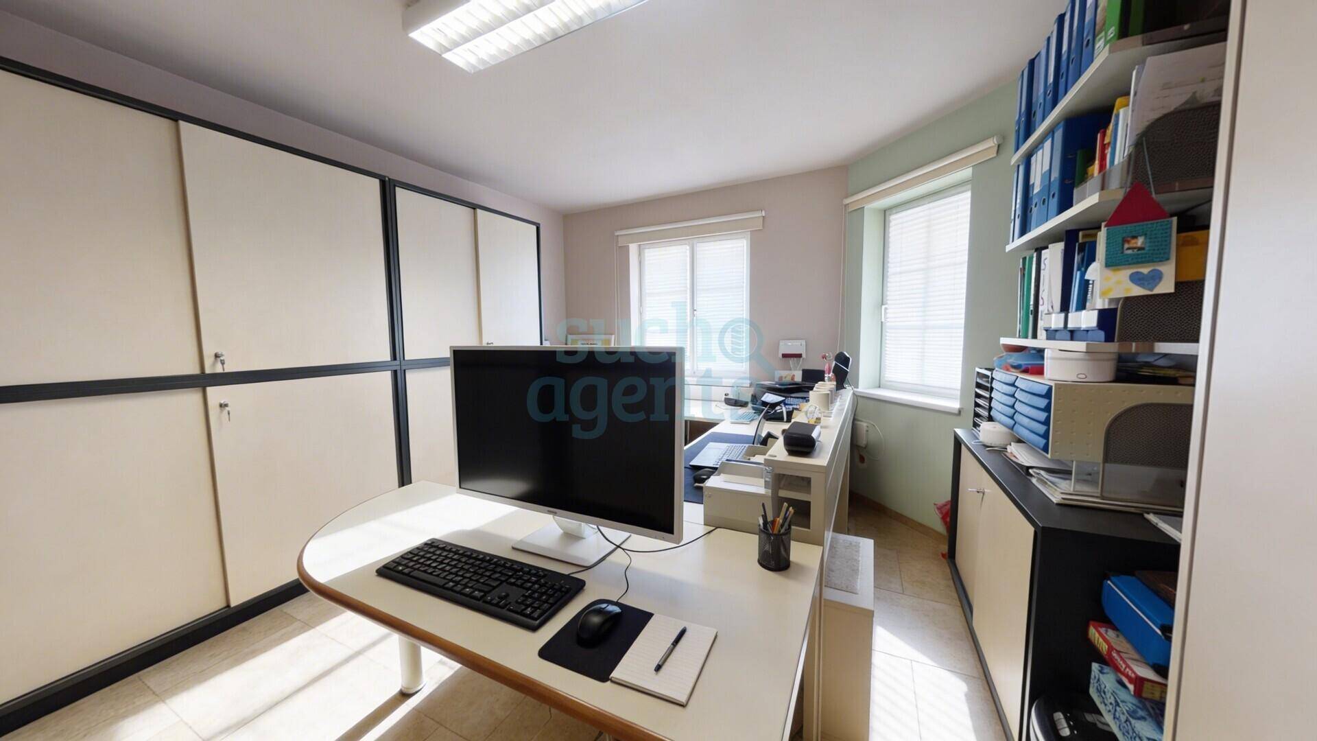 Funktionales Büro mit Schreibtisch, Computer und integrierten Wandschränken für Stauraum.