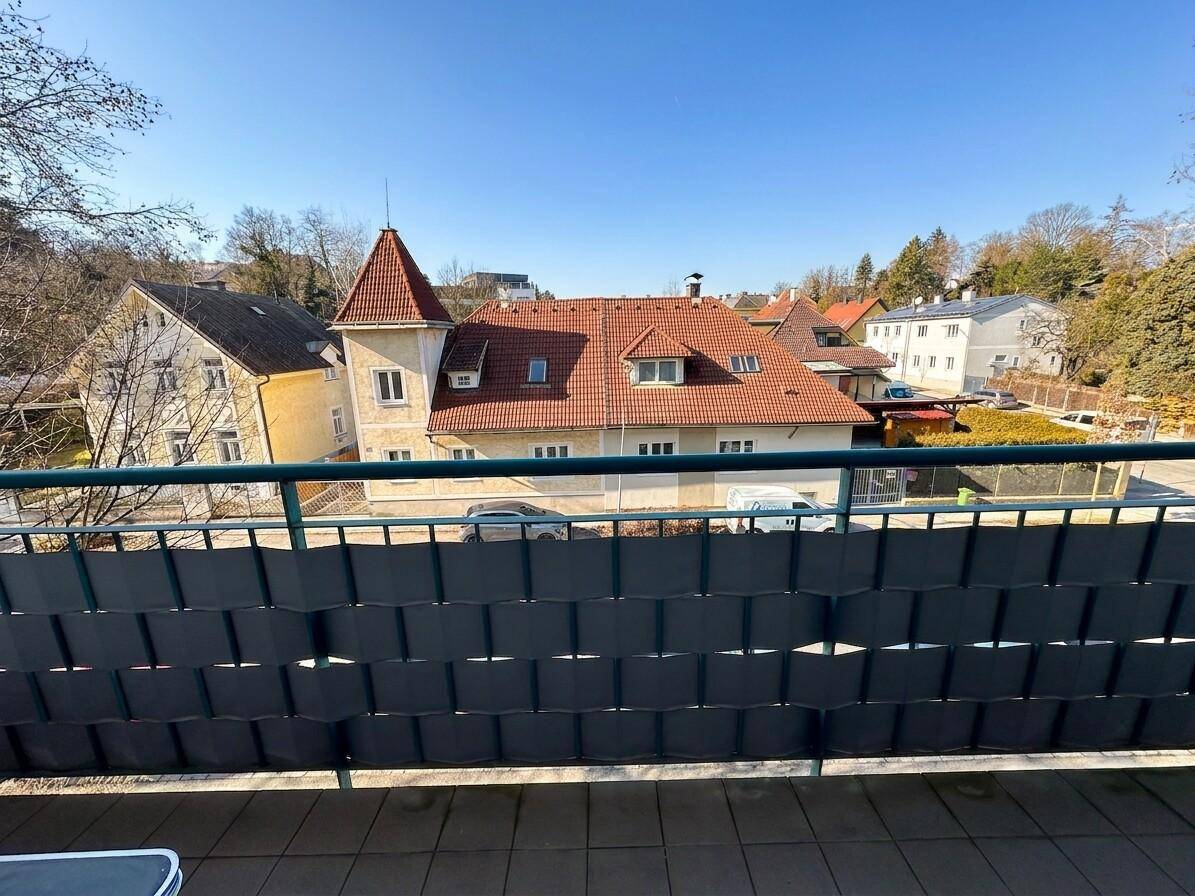 Blick vom Balkon auf die umliegenden Wohnhäuser und grüne Umgebung an einem sonnigen Tag.