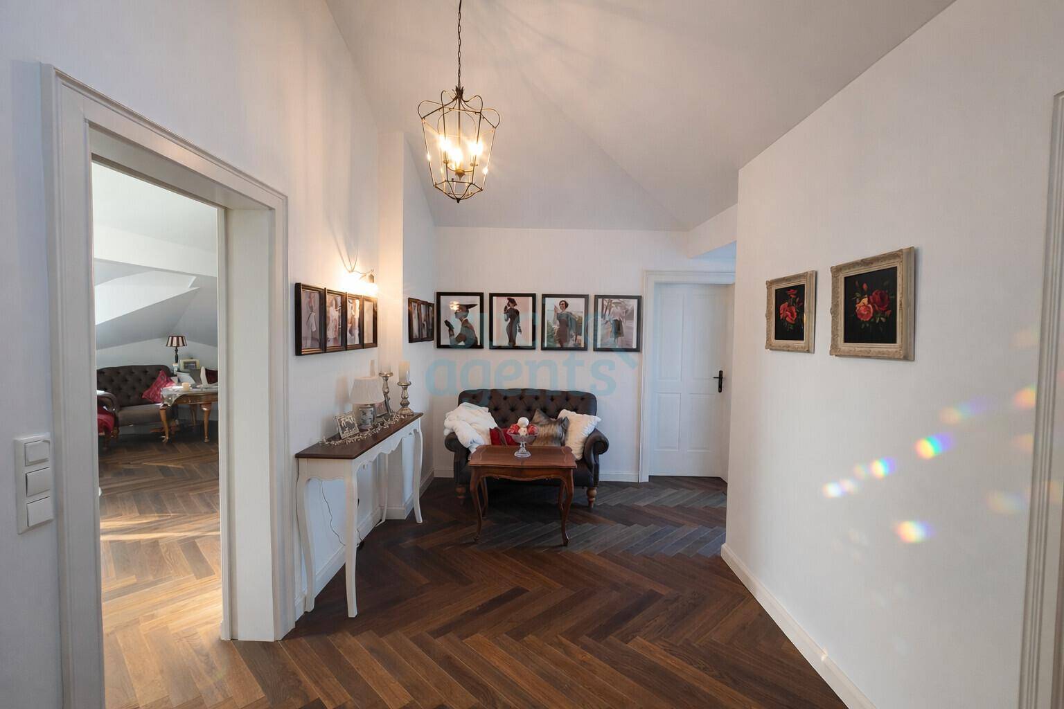 Eleganter Flur mit Fischgrätparkett, hohen Decken und stilvoller Dekoration, der zu weiteren Räumen führt.