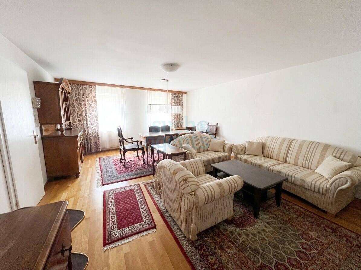 Klassischer Wohn-Essbereich mit gestreiften Sofas, Holztisch und traditionellen Teppichen.