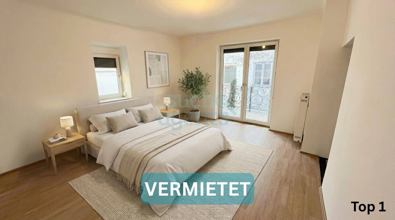 Gemütliches Schlafzimmer mit Doppelbett, Holzboden und Zugang zu einem kleinen Balkon.
