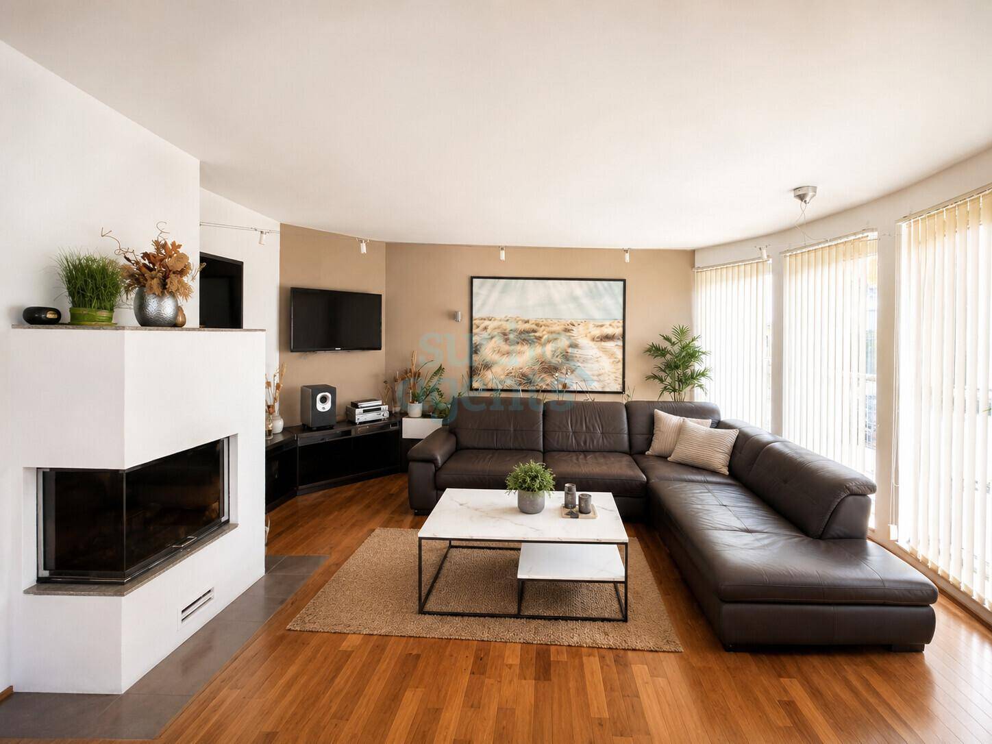 Gemütliches Wohnzimmer mit großem Ecksofa, Kamin und Holzboden, hell durch große Fenster.