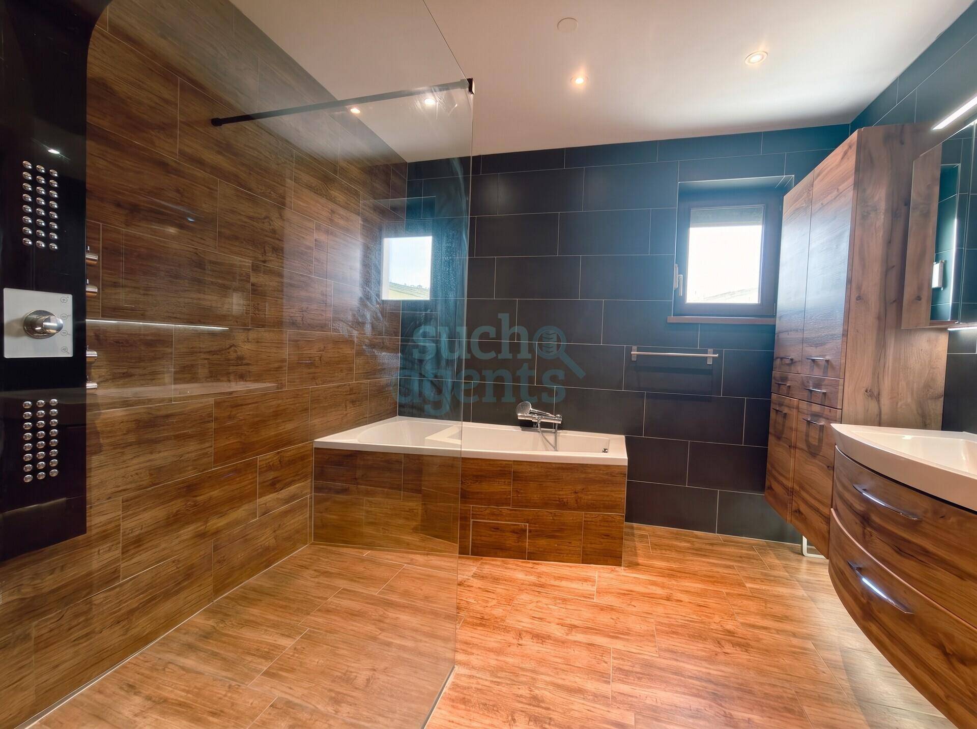 Modernes Badezimmer mit Badewanne, begehbarer Dusche, Doppelwaschbecken und Holzoptik-Fliesen.