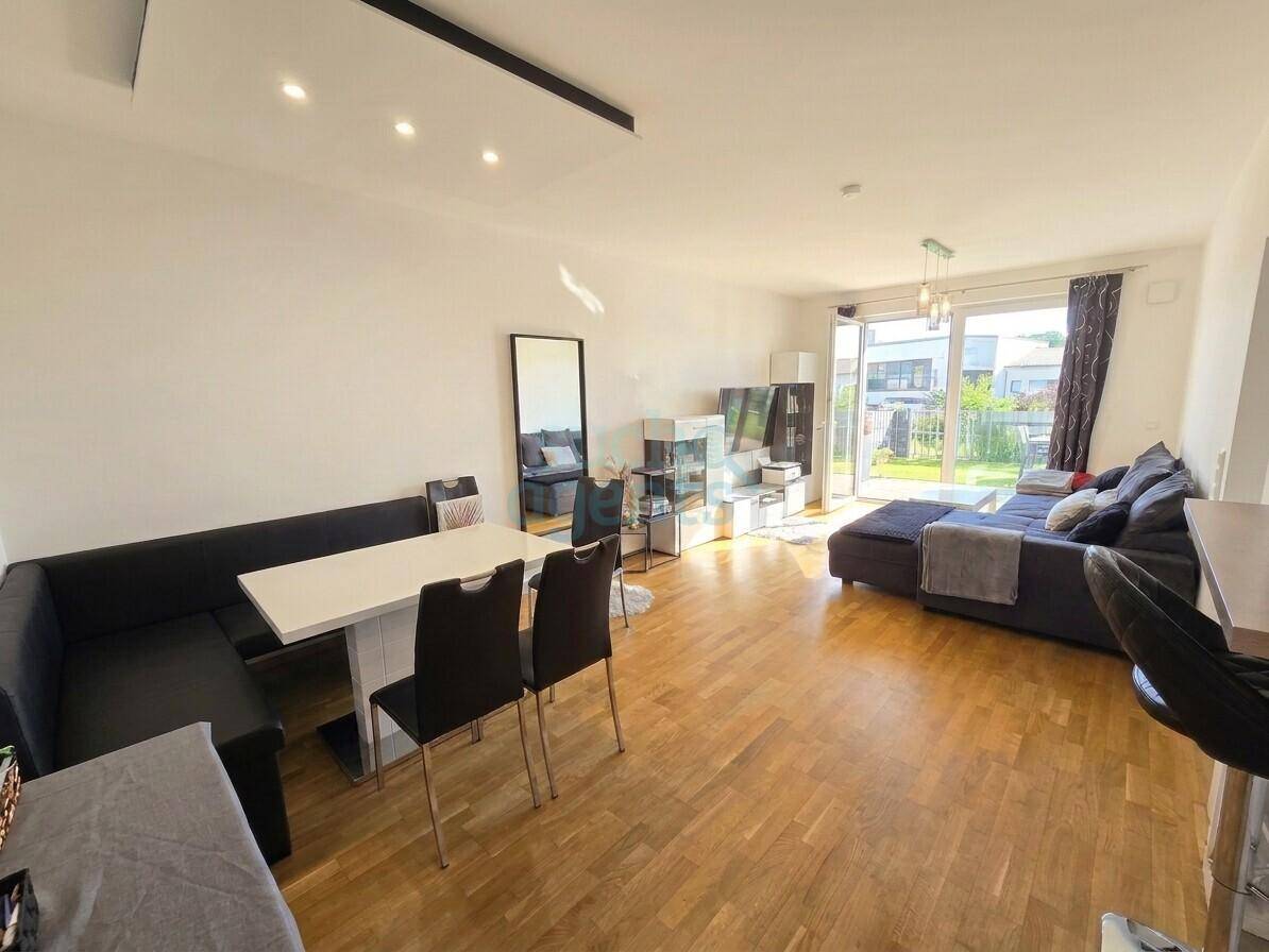 Offener Wohn- und Essbereich mit Holzboden, gemütlicher Sitzecke und Zugang zum Garten.