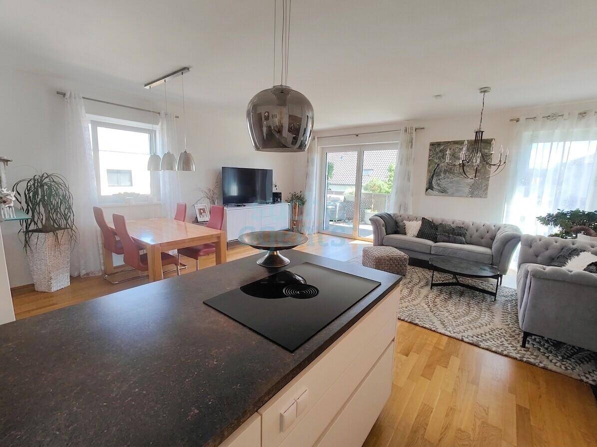 Geräumiger Wohn-Essbereich mit offener Küche, Zugang zum Balkon und viel natürlichem Licht.