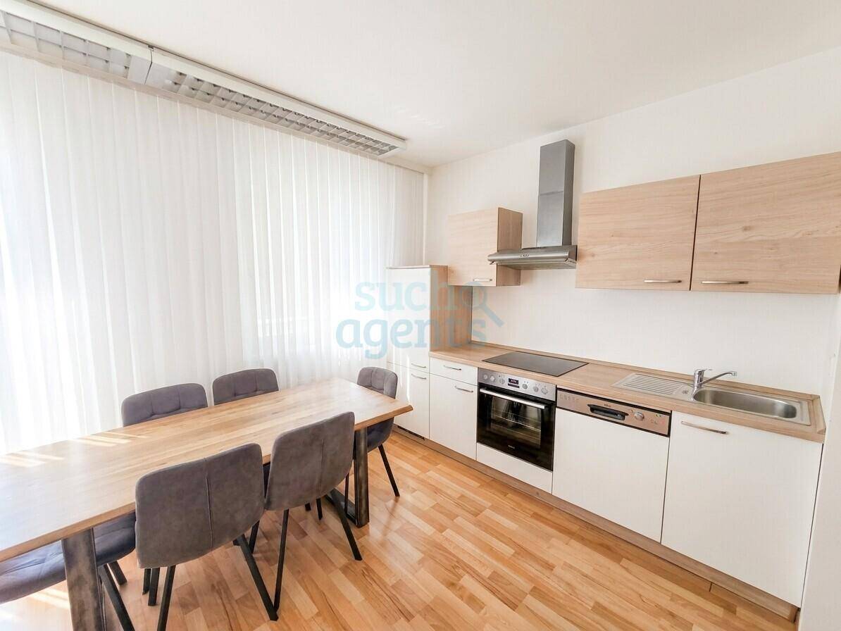 Moderne Einbauküche mit hellen Holzfronten, integrierten Geräten und Essbereich.