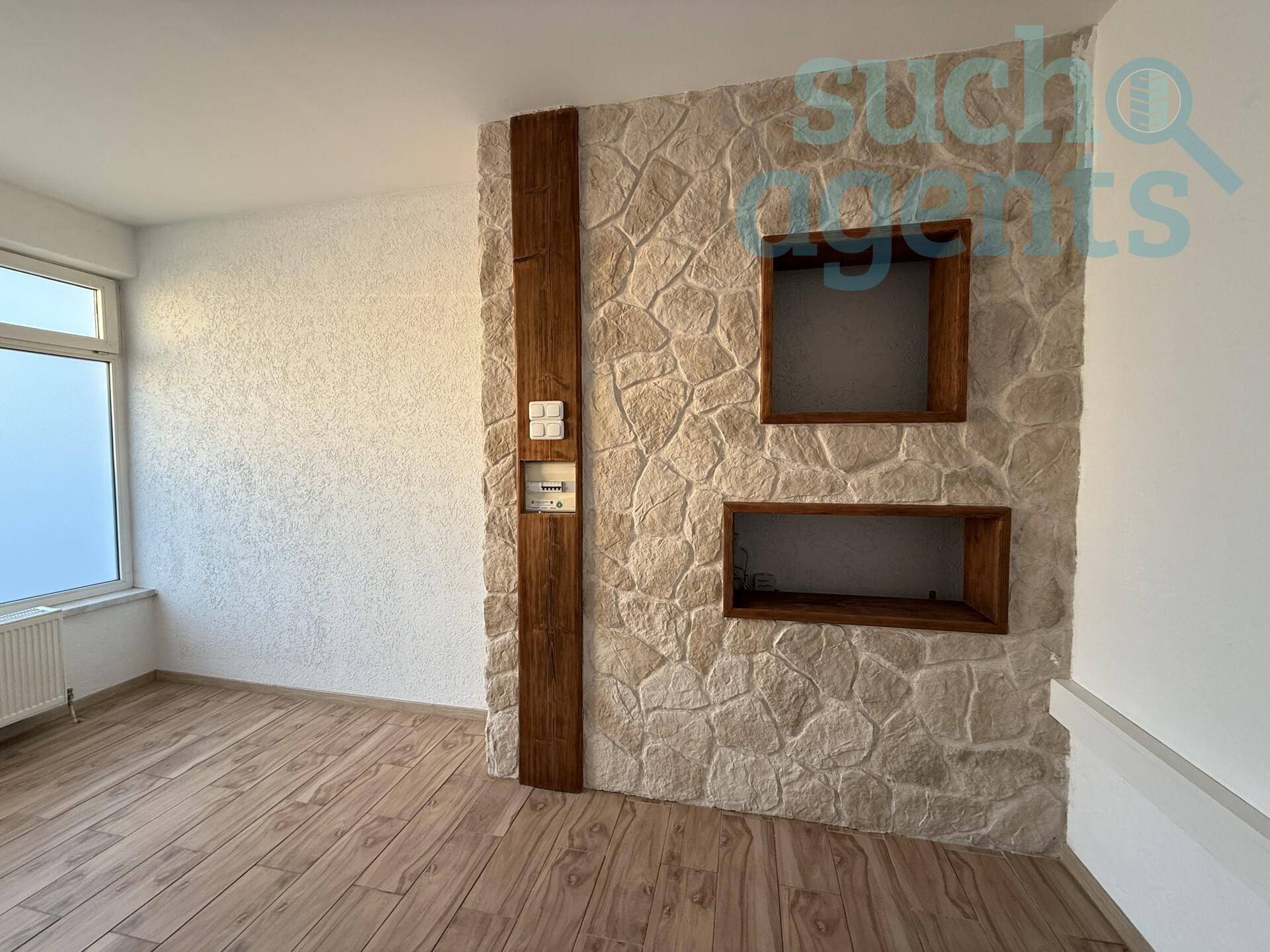 Wohnraum mit Steinwand, Holzakzenten und Fenster für natürliches Licht.