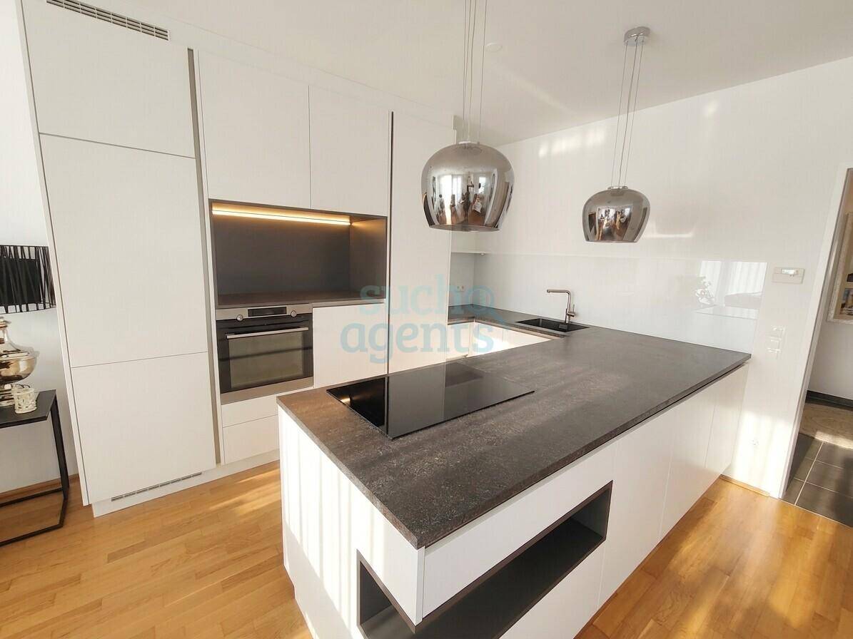 Moderne Einbauküche mit weißen Schränken, integriertem Backofen und Kochinsel mit Induktionskochfeld.