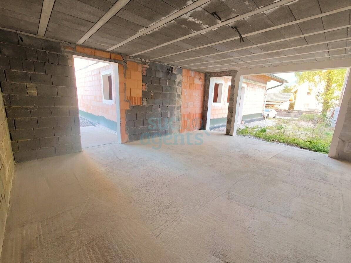 Unfertiger Kellerbereich mit Betonboden und unverputzten Wänden, mit Zugang zu weiteren Räumen.