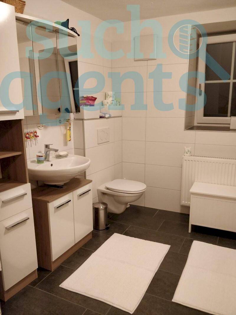 Modernes Badezimmer mit weißen Fliesen, dunklem Boden und Fenster.