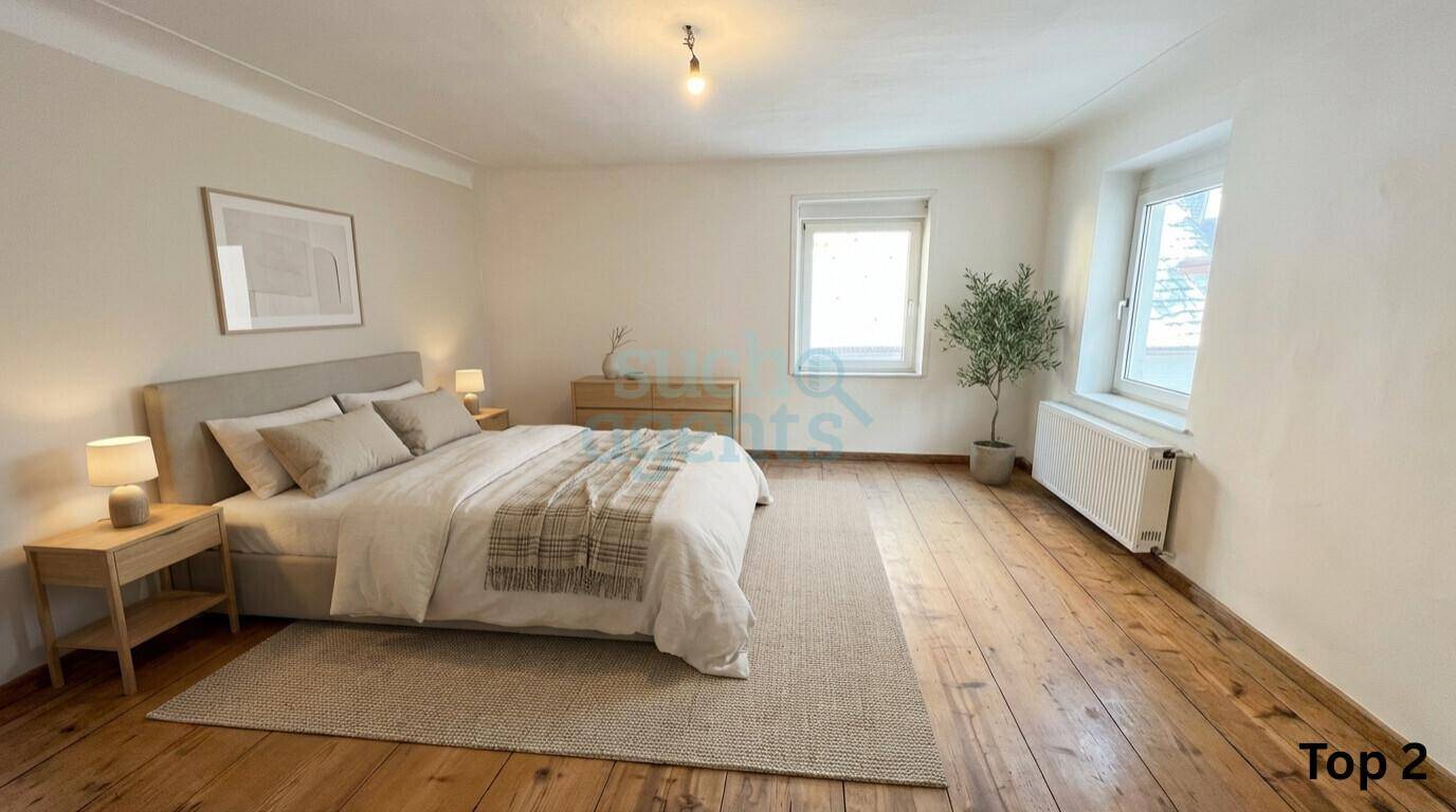 Geräumiges Schlafzimmer mit Holzdielenboden, Doppelbett und viel Tageslicht.