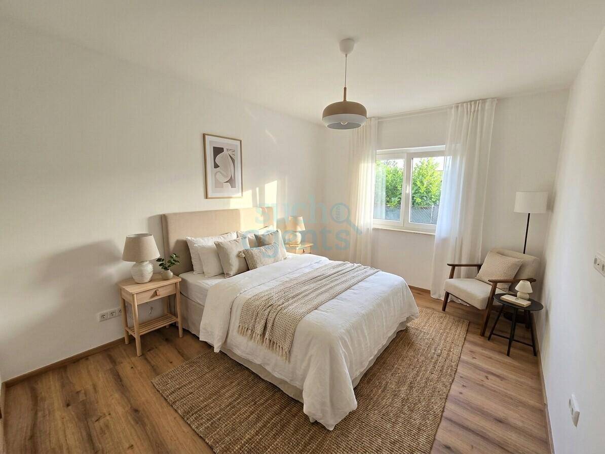 Sonnenverwöhntes Schlafzimmer mit hellem Laminatboden, modernem Bett und schlichter, eleganter Einrichtung.