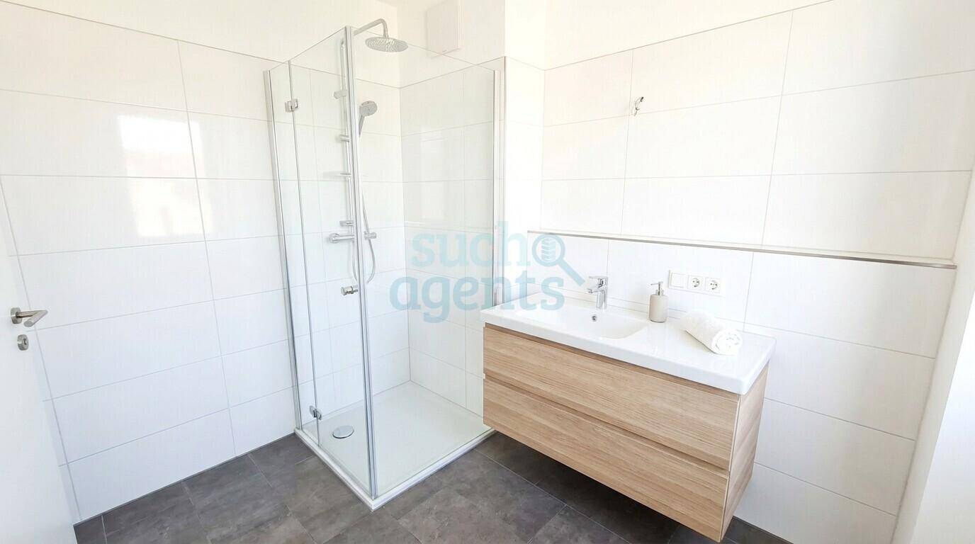 Modernes Badezimmer mit großer Duschkabine, schwebendem Waschtisch und weißen Fliesen.