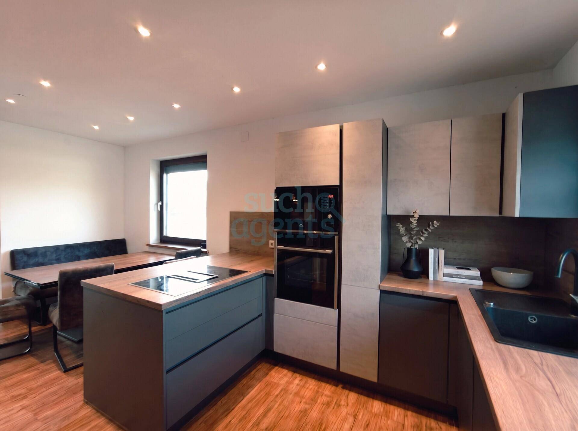 Moderne Einbauküche mit Kochinsel, integriertem Backofen und Essbereich mit Holztisch.