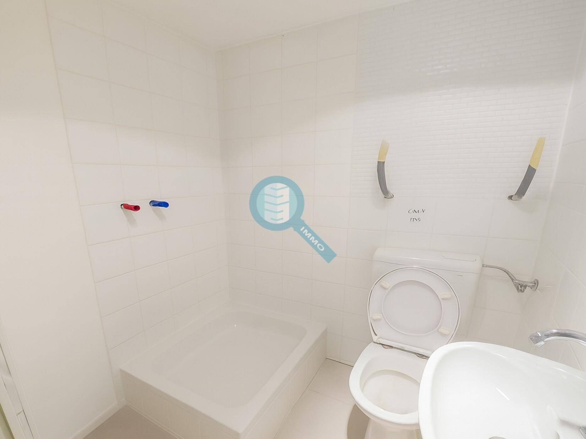 Kleines Badezimmer mit weißen Fliesen, einer Toilette und einem Duschbereich, der noch fertiggestellt werden muss.