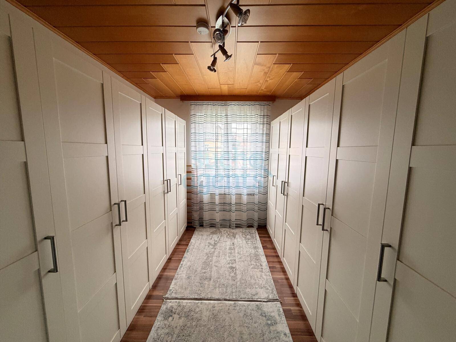 Heller Flur mit beidseitigen Einbauschränken und Holzdecke.