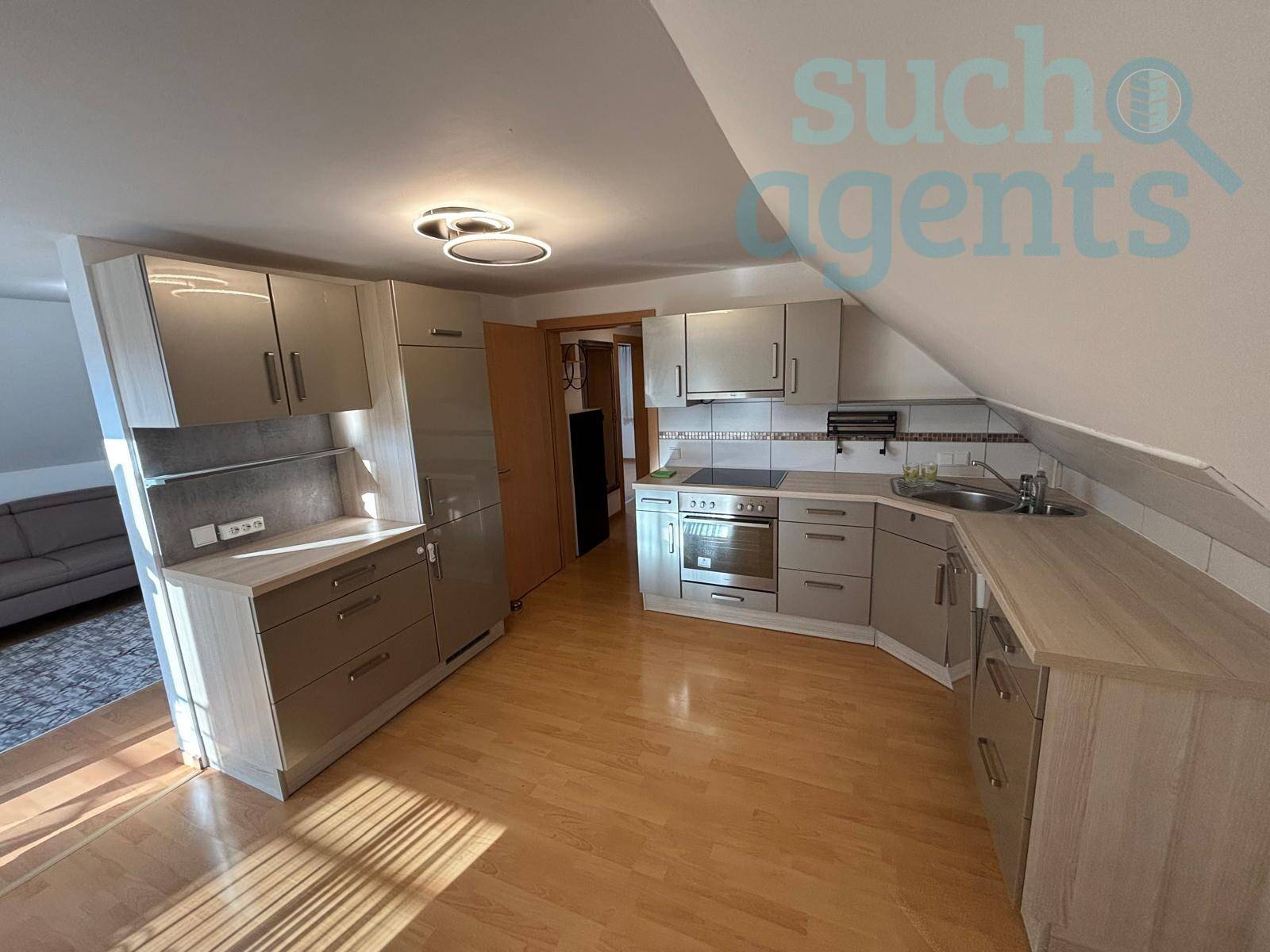 Moderne Küche mit Dachschräge, Einbaugeräten und hellem Holzboden.