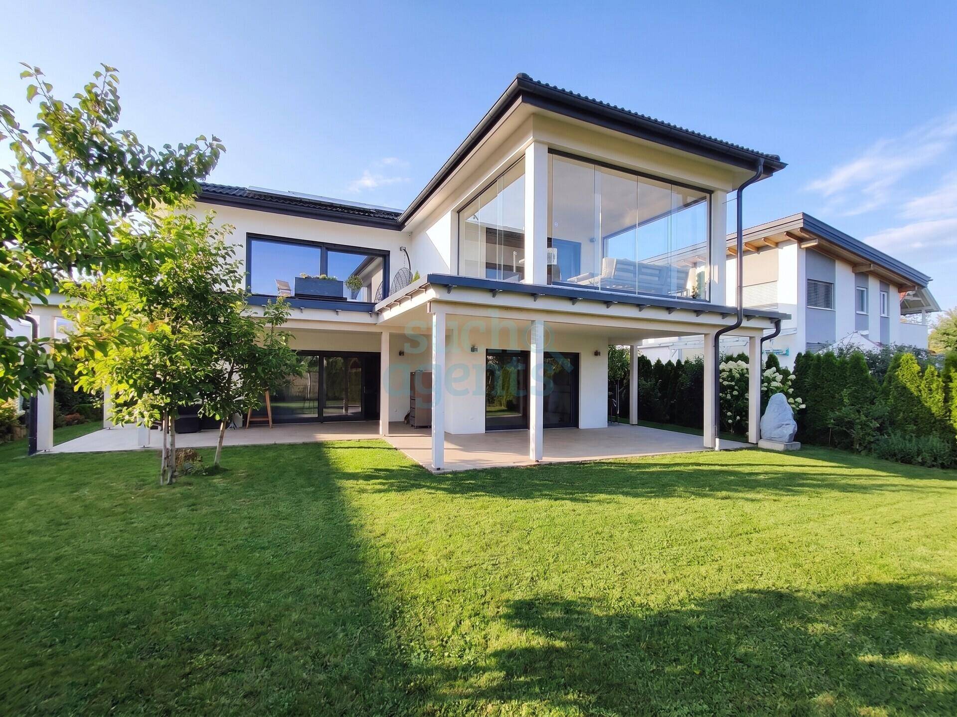 Modernes Einfamilienhaus mit großer Rasenfläche und verglastem Obergeschossbereich.