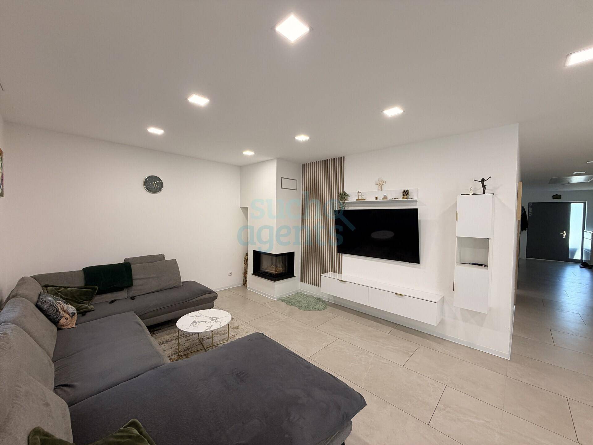Gemütliches Wohnzimmer mit großem Sofa, modernem Kamin und Wandfernseher.