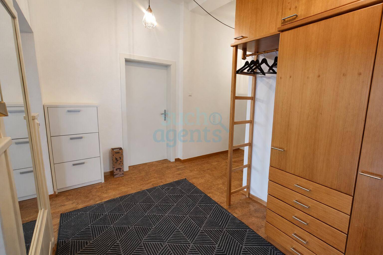 Funktionaler Flurbereich mit Holzschrank, Schuhregal und Teppichboden.