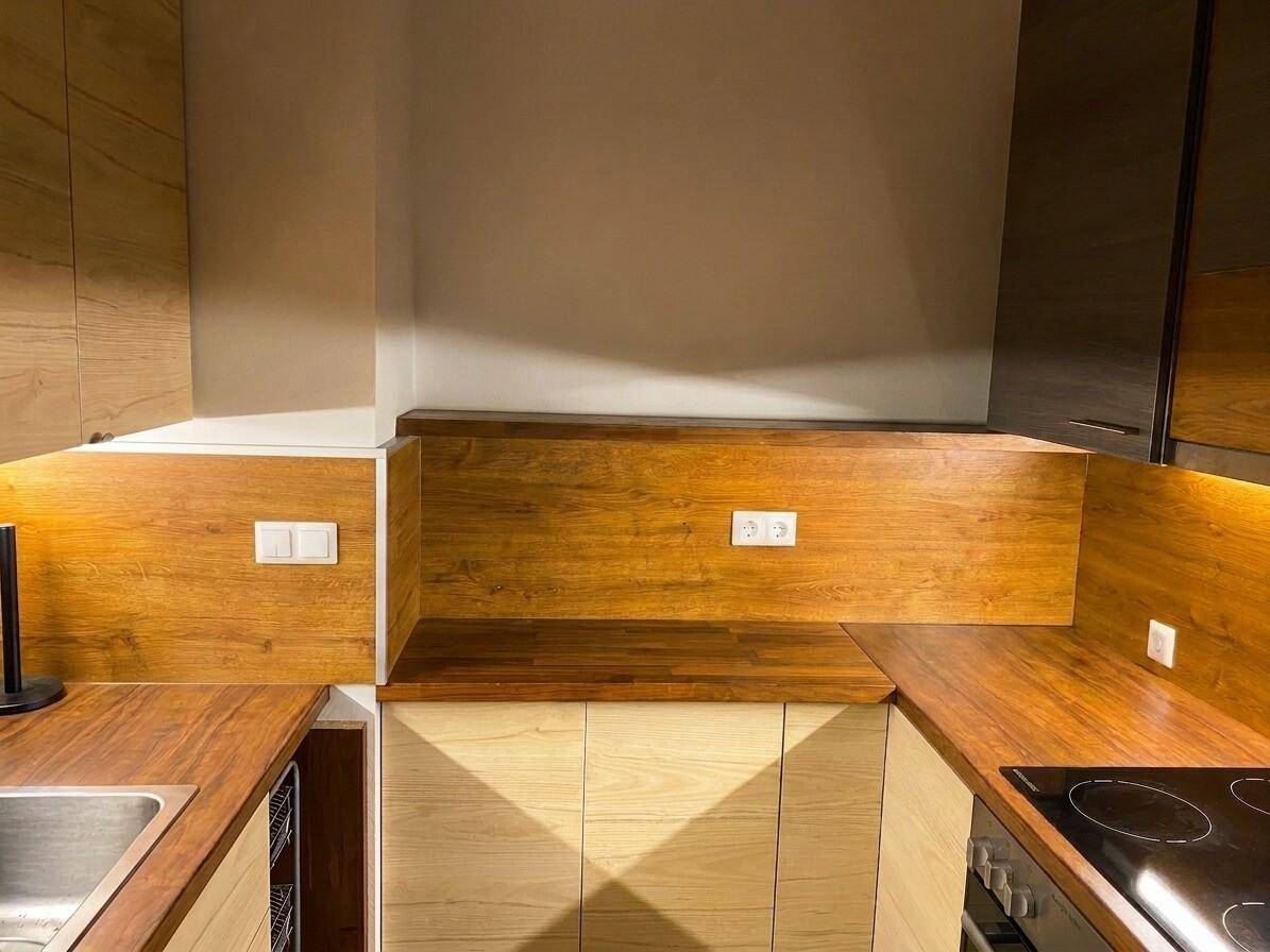 Moderne Küche mit Holzfronten, Arbeitsplatten und Induktionskochfeld.