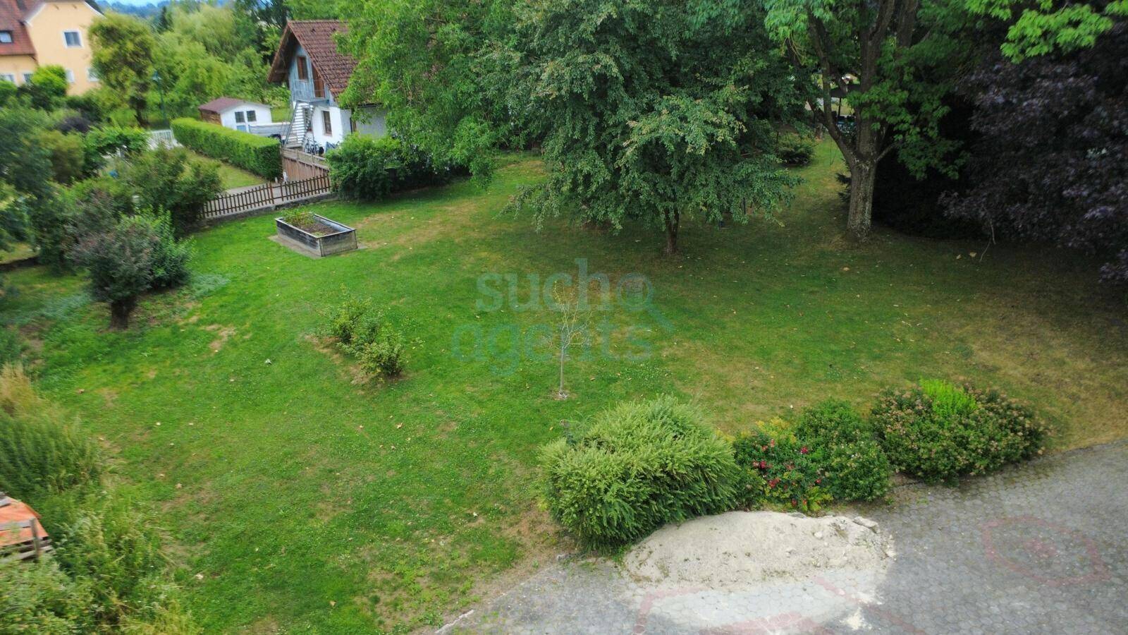 Blick von oben auf einen grünen Gartenbereich mit altem Baumbestand und Rasenfläche.