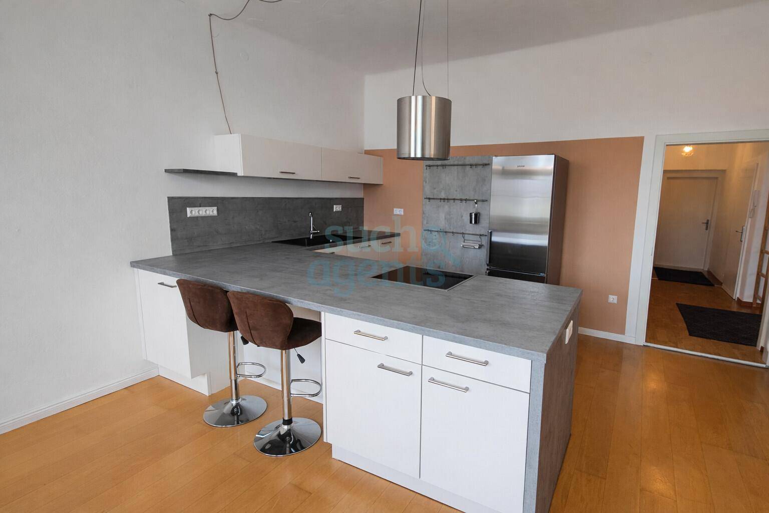 Moderne Küche mit Kücheninsel, integriertem Kochfeld und Barhockern für geselliges Beisammensein.
