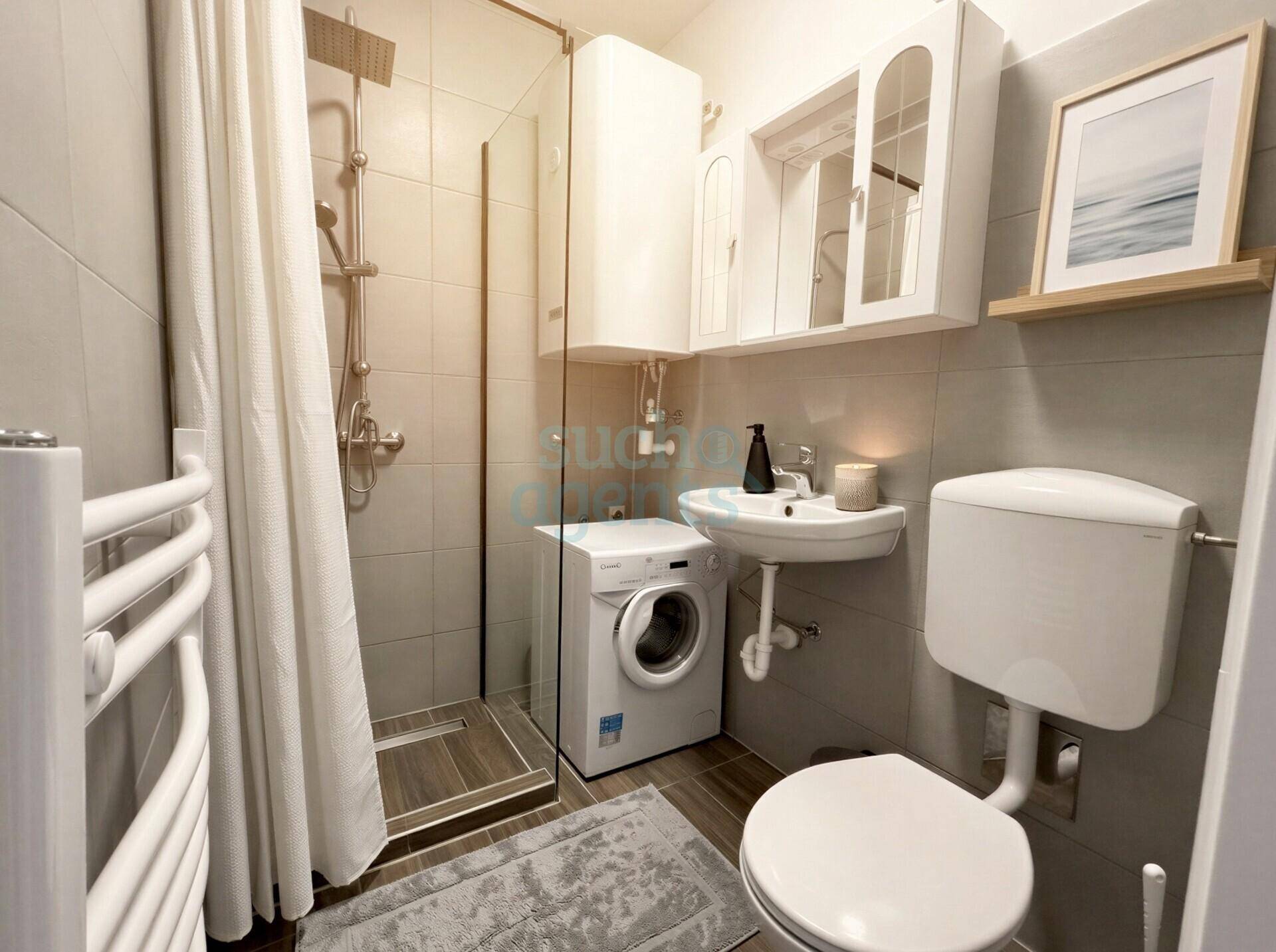 Modernes Badezimmer mit Duschkabine, Waschbecken, Toilette und integrierter Waschmaschine.
