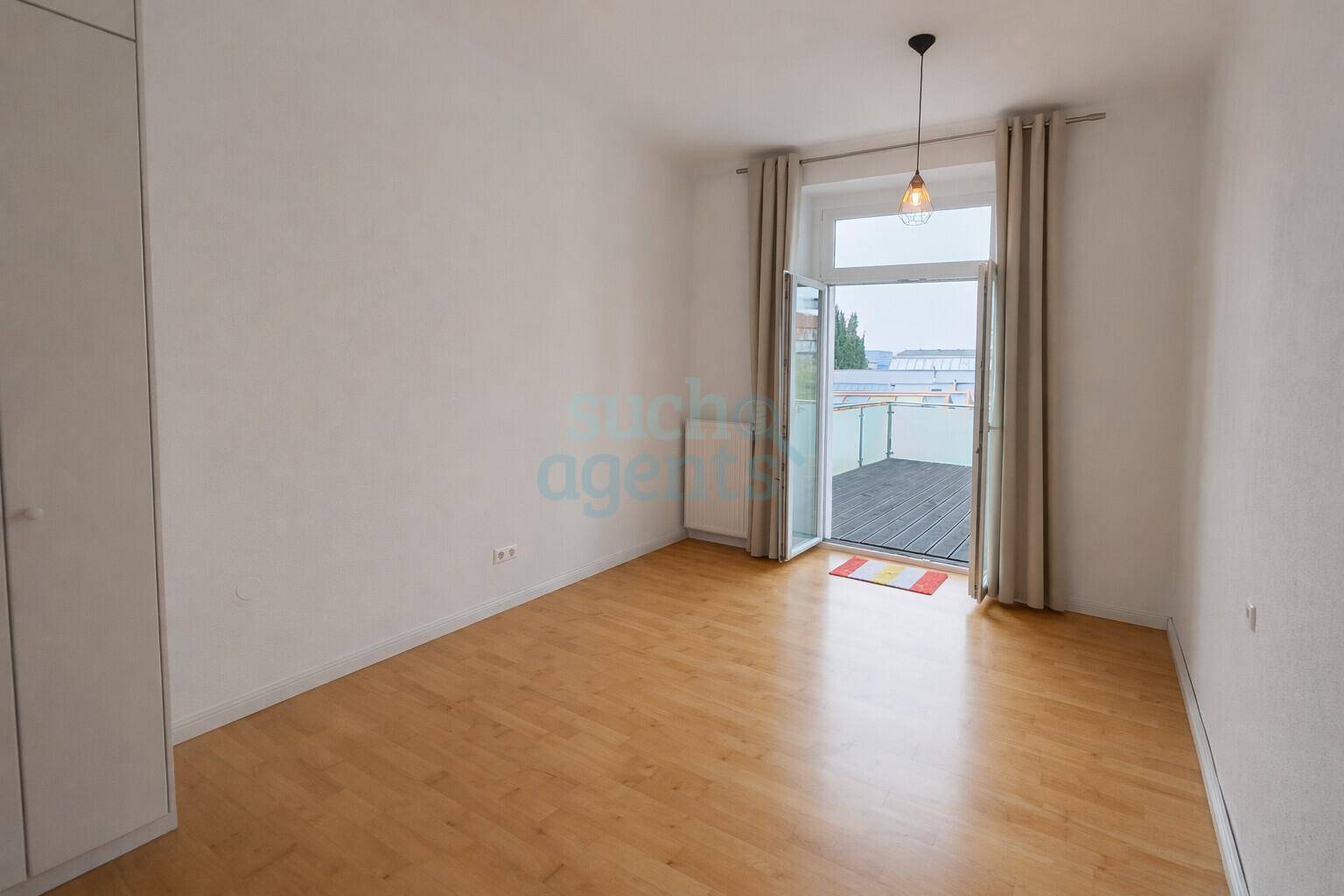 Heller Raum mit Holzboden und direktem Zugang zu einem Balkon.