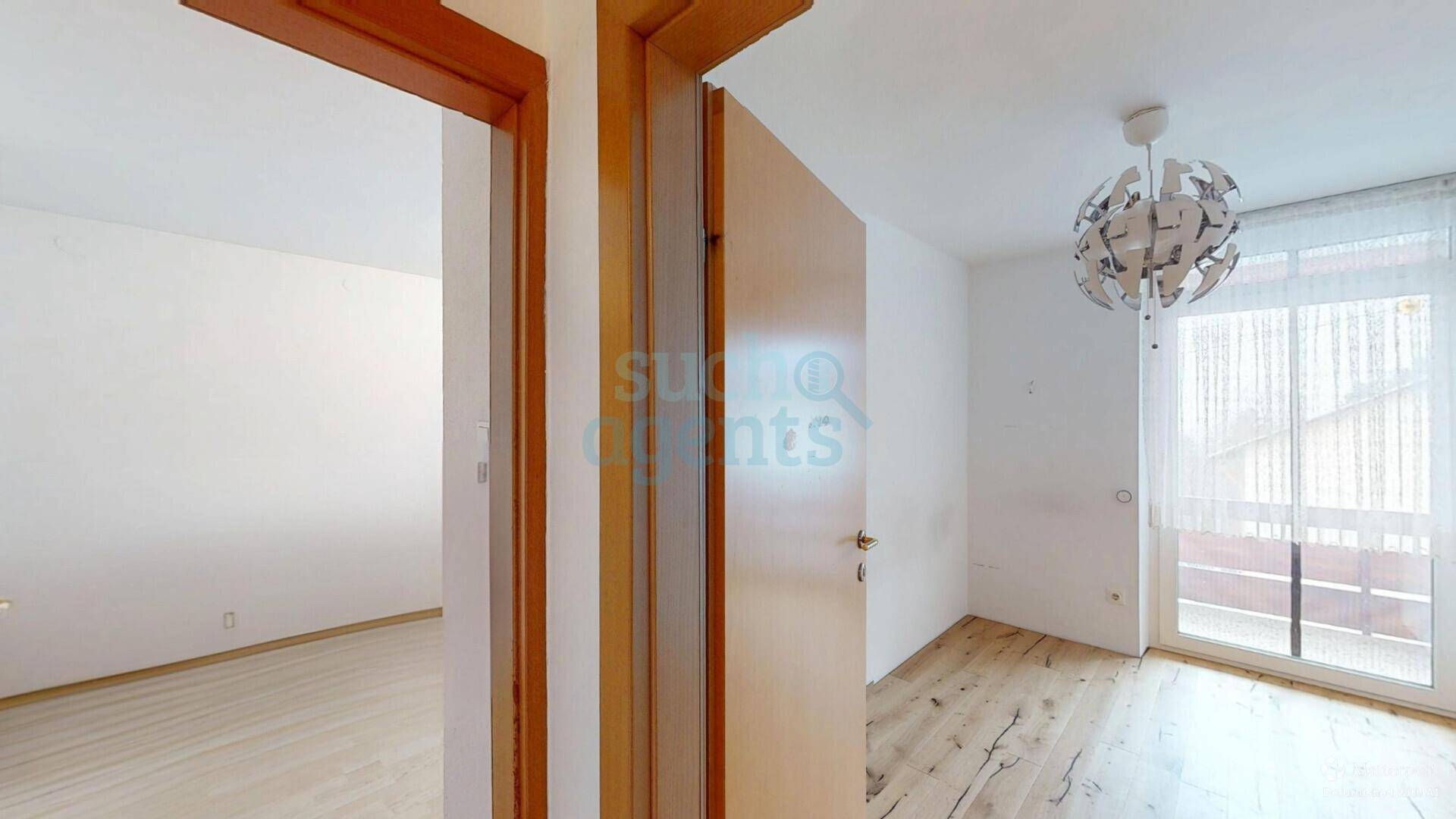 Leeres Zimmer mit Holzboden und Zugang zu einem Balkon, bereit zur individuellen Gestaltung.