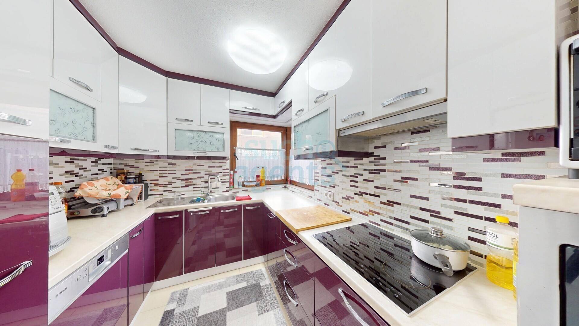 Moderne Küche mit weißen und violetten Schränken, Induktionskochfeld und Fliesenrückwand.