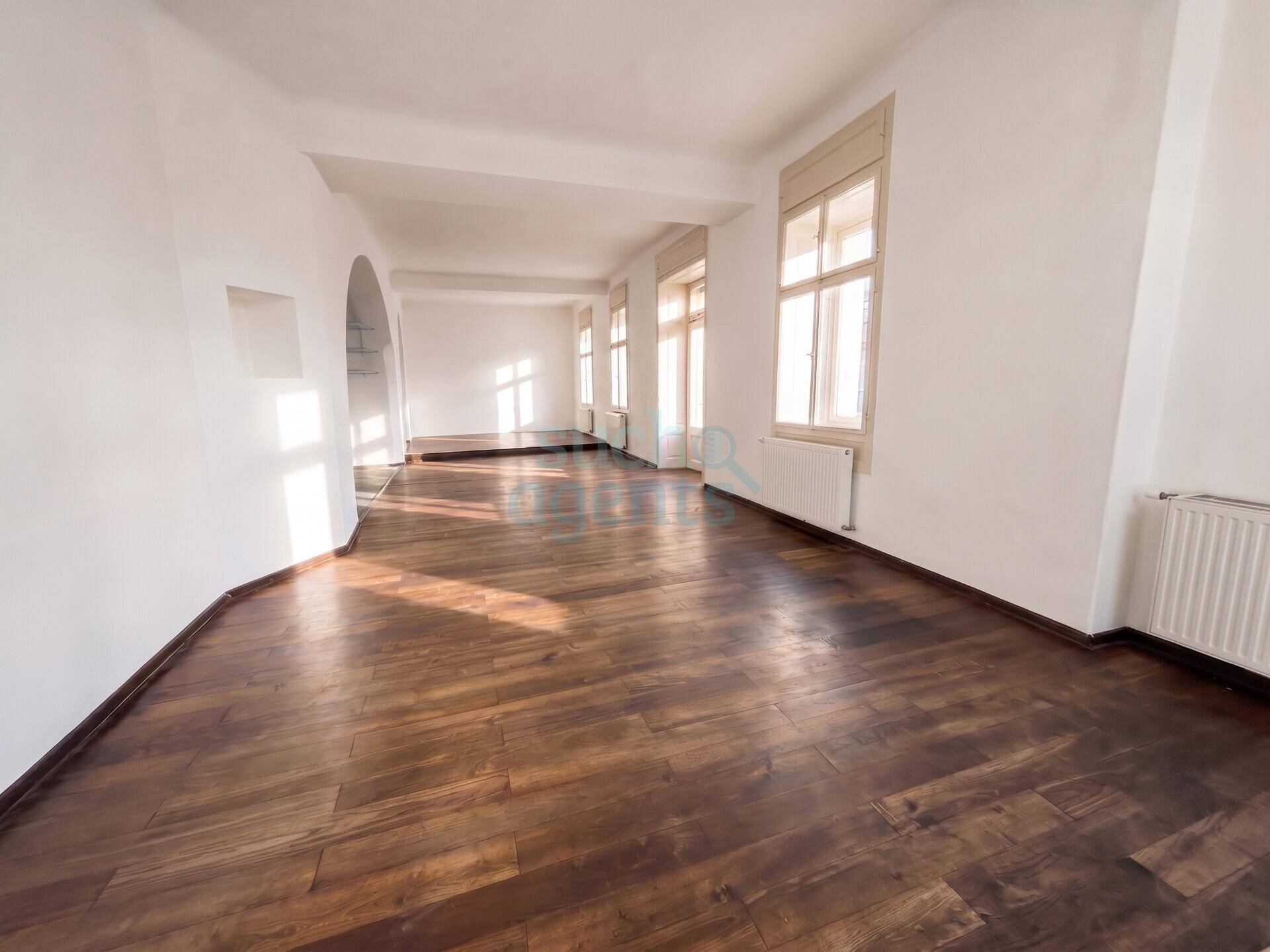 Heller und geräumiger Wohnbereich mit dunklem Holzfußboden, weißen Wänden und viel natürlichem Lichteinfall.