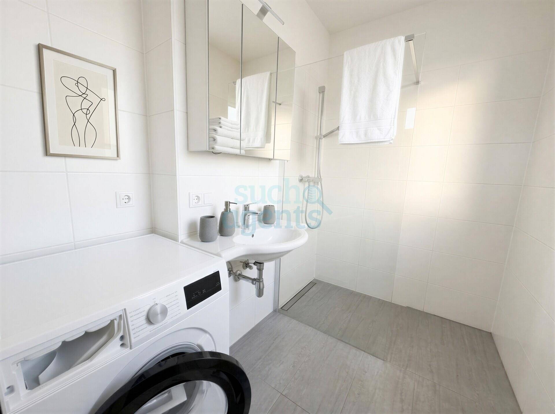 Modernes Badezimmer mit Dusche, Waschbecken, Spiegelschrank und Waschmaschine.