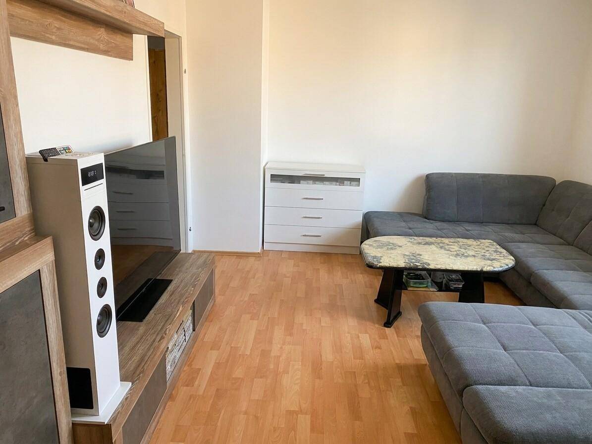 Gemütlicher Wohnbereich mit grauem Ecksofa, Couchtisch und Medienschrank.